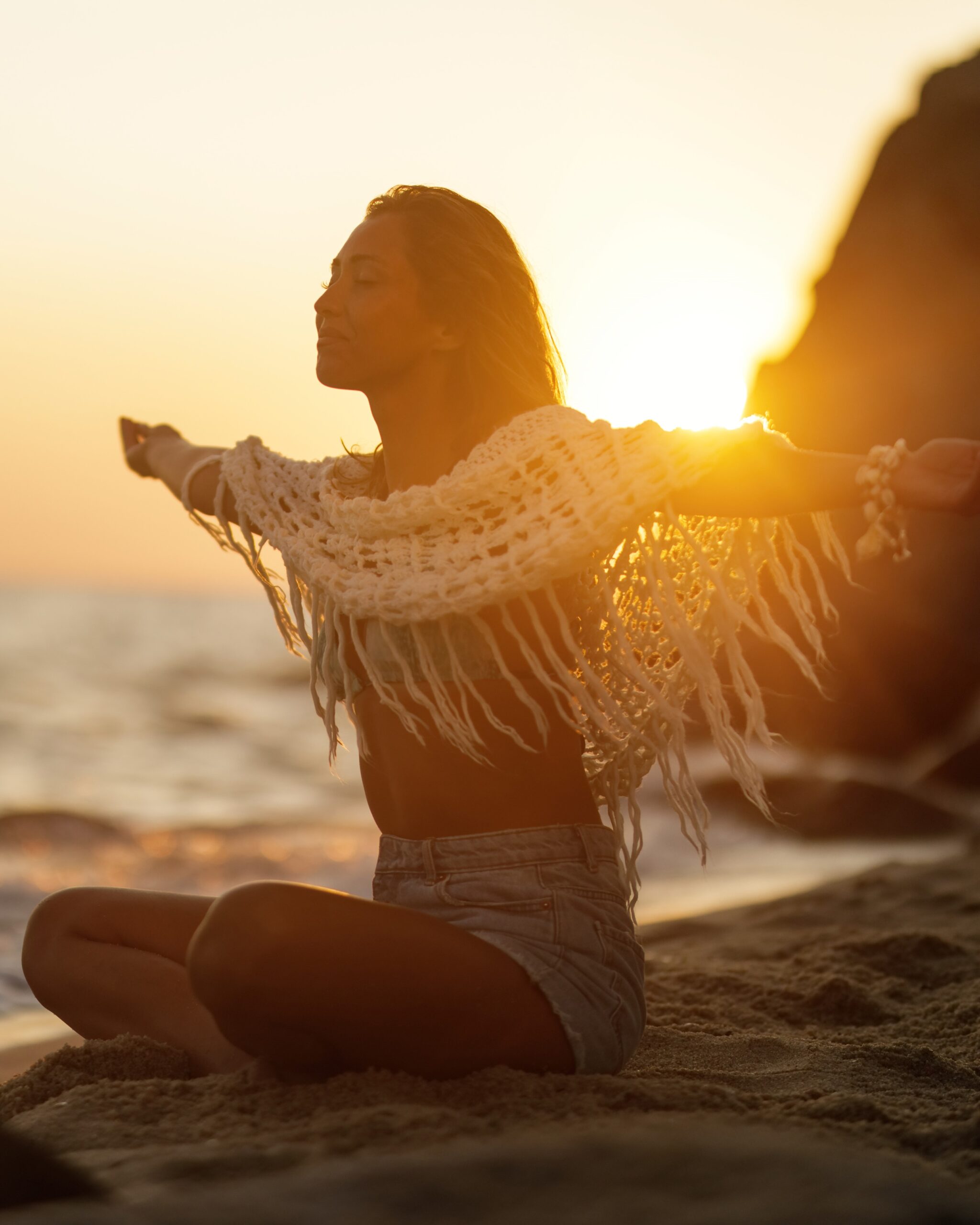 Smiling woman with arms outstretched feeling free at summer sunset.